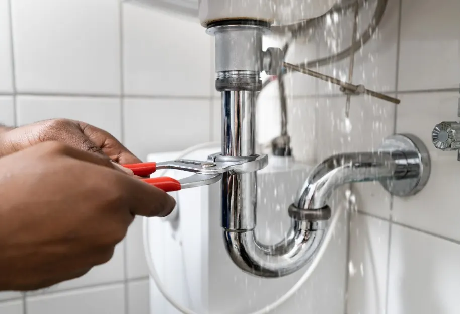 Fontanero ajustando el sifón y la grifería de un lavabo
